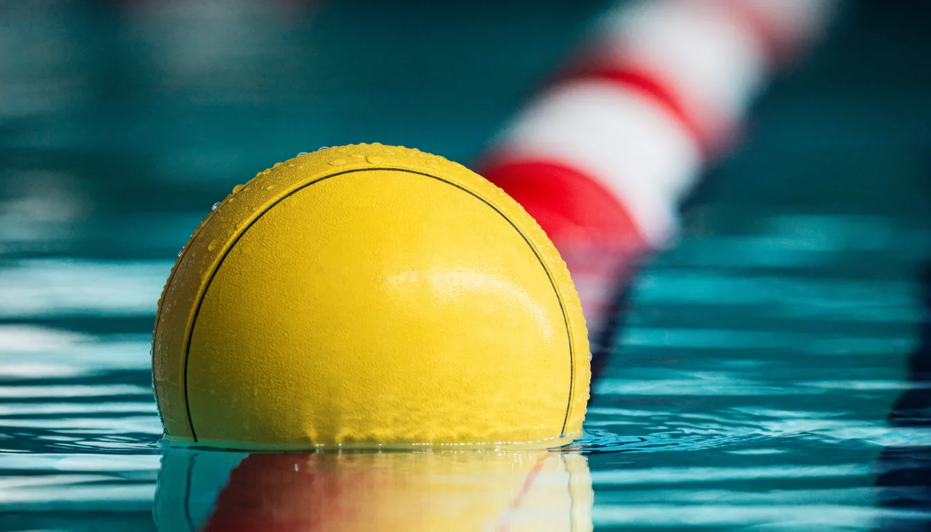 Ein gelber Wasserball treibt in Nahaufnahme auf der Wasseroberfläche neben einer Leine mit Bojen.